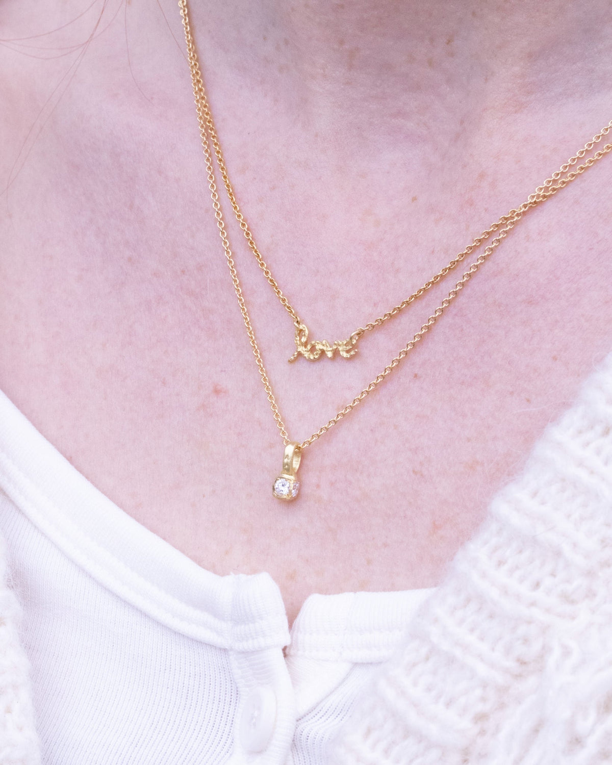Goldkette mit Love-Schriftzug um den Hals getragen, kombiniert mit funkelndem Anhänger