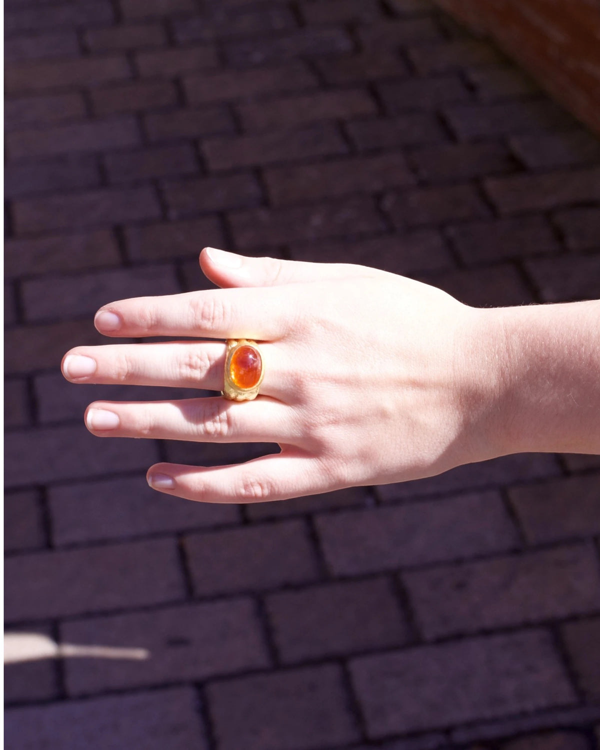 750 Goldring mit Mandarin-Granat 17,30 ct, an der Hand getragen im Sonnenlicht