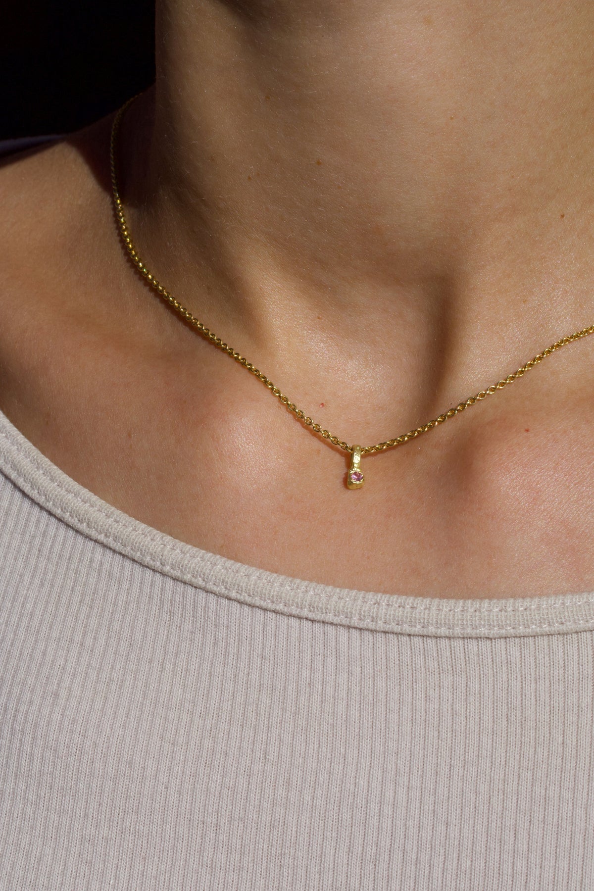 Zarter Würfelanhänger aus 750 Gold mit pinkem Saphir (0,03 ct), getragen