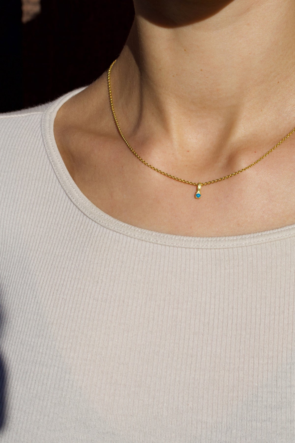 Zarter Würfelanhänger aus 750 Gold mit Türkis (2 mm) und 750 Goldkette, getragen