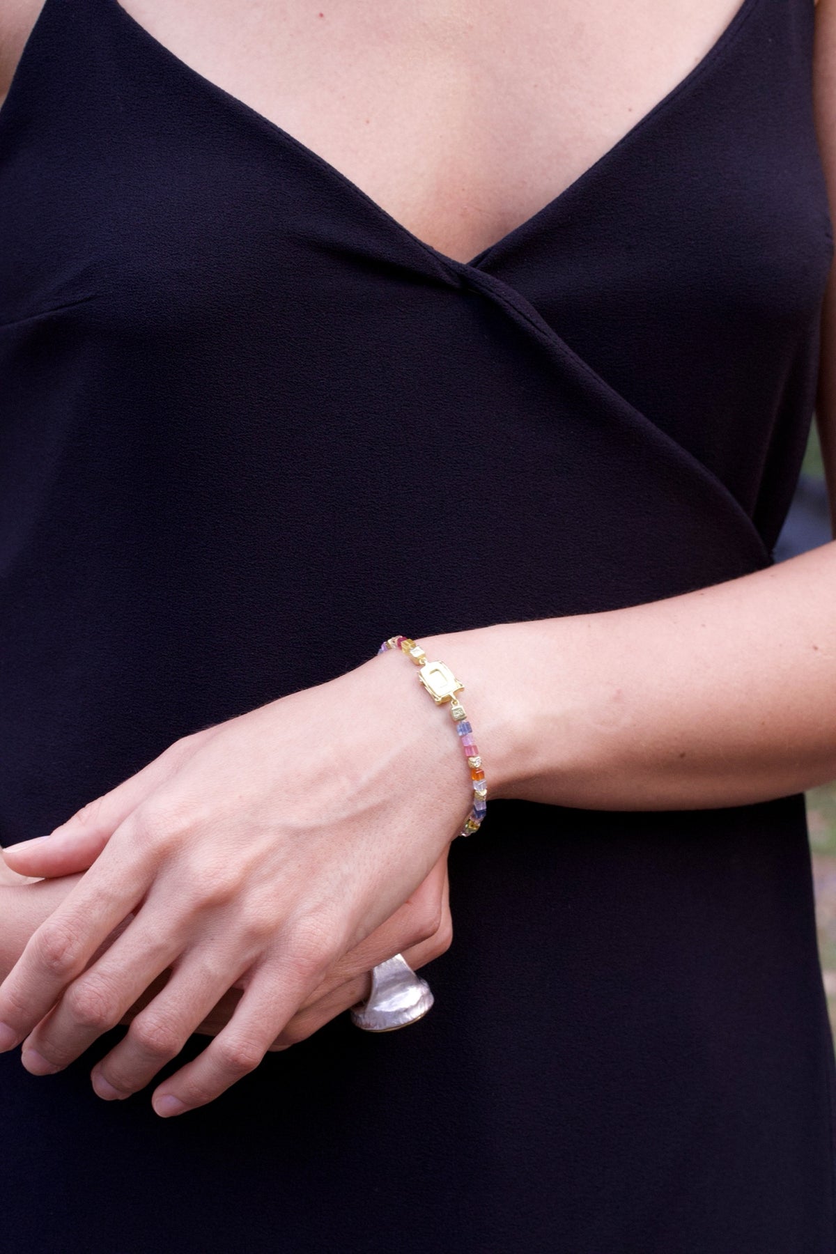 Buntes Saphirarmband mit Goldwürfeln am Handgelenk einer Frau