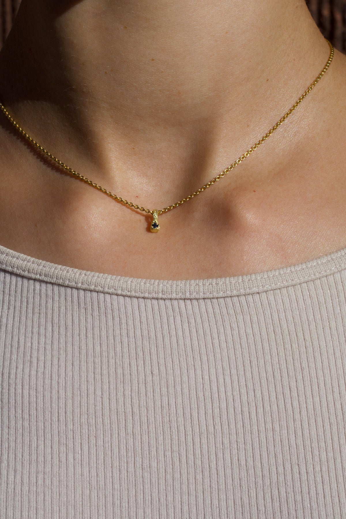 Zarter Würfelanhänger aus 750 Gold mit blauem Saphir (0,025 ct) und 750 Goldkette, getragen
